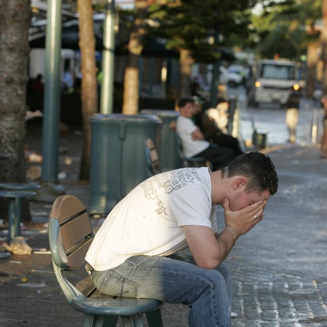 A young man sits with head in hands in Cavill Avenue, Surfers Paradise on the Gold Coast in the early morning, after the first official night of Schoolies Week.