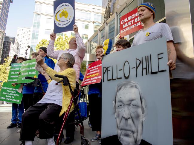 Protesters hold placards outside the County Court as they await Cardinal George Pell in Melbourne on Wednesday. Picture: AP/Andy Brownbill.