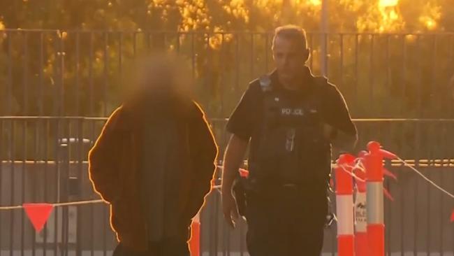 One of the alleged victim of Lobethal stabbing being walked into hospital alongside a police officer. 7News Adelaide.