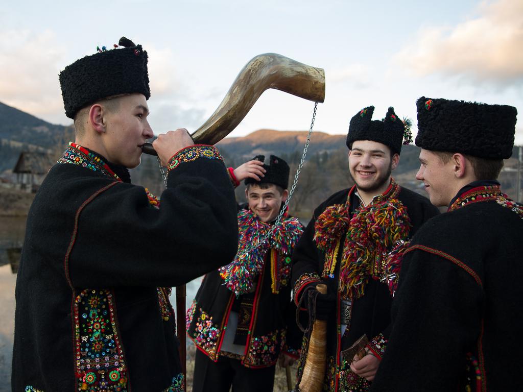 A young man plays a horn while the group of carolers walk from house to house singing for families during the Christmas period. Ukrainians living in the Verkhovyna region wear traditional Hutsul clothing to take part in Orthodox Christmas celebrations. Picture: Getty