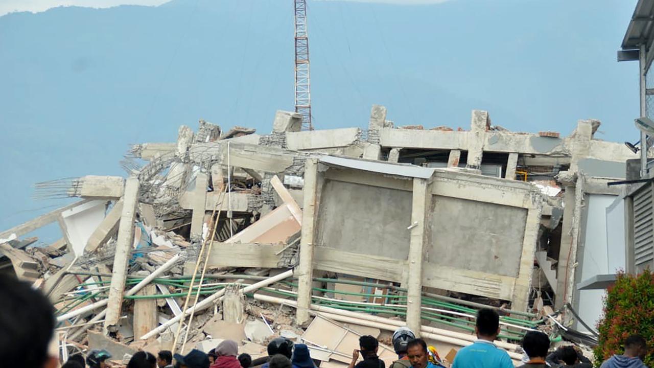 Residents gather to look at a collapsed building. Picture: AFP