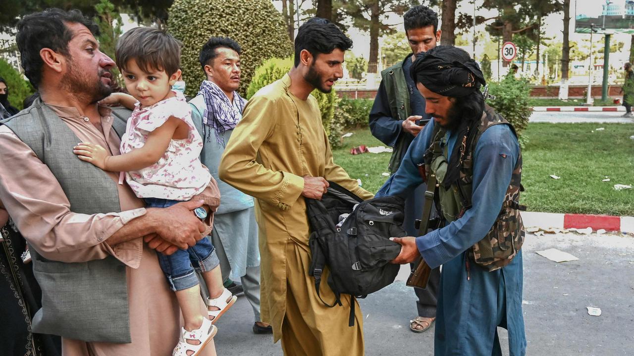 A Taliban fighter searches the bags of people exiting Kabul International Airport. Picture: AFP