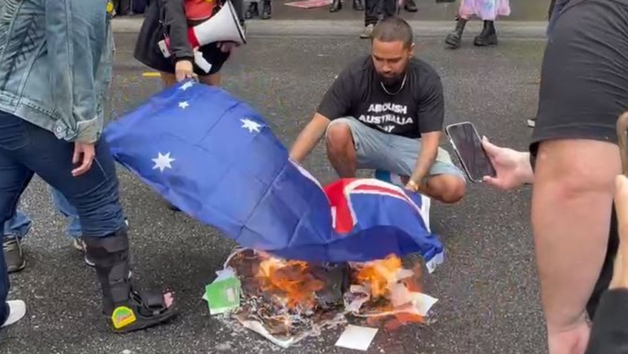 An Australian flag is burnt during a protest in Brisbane's CBD. Picture: Matthew Johnston