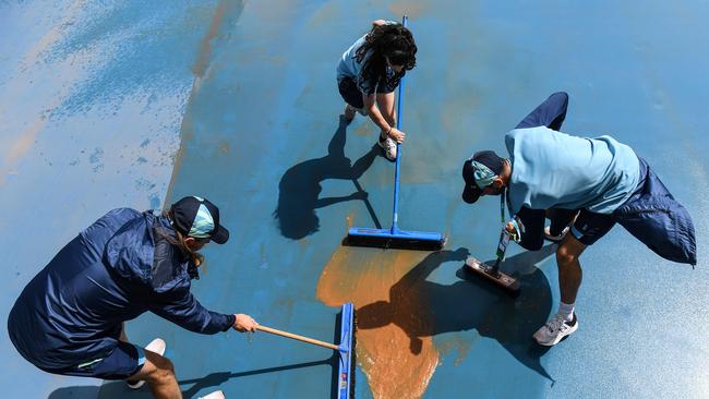 Workers clean a court after overnight rain delayed play to start day four. Picture: AFP