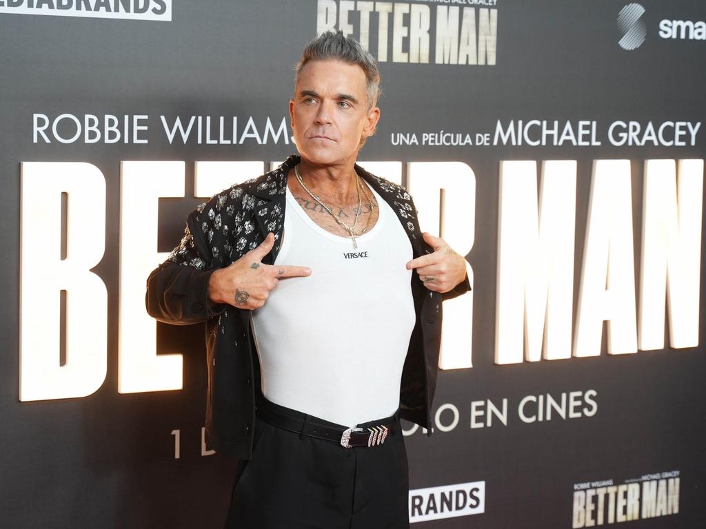 Robbie Williams points out his Versace branded singlet as he walked the red carpet at the Madrid premiere of his autobiographical film ‘Better Man’. Picture: Backgrid