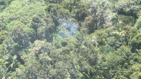 Smoke rising from the thick tree coverage of a mountain range north of Okuloo and Netherdale where a plane crashed on Saturday, October 28, 2023. Picture: RACQ CQ Rescue