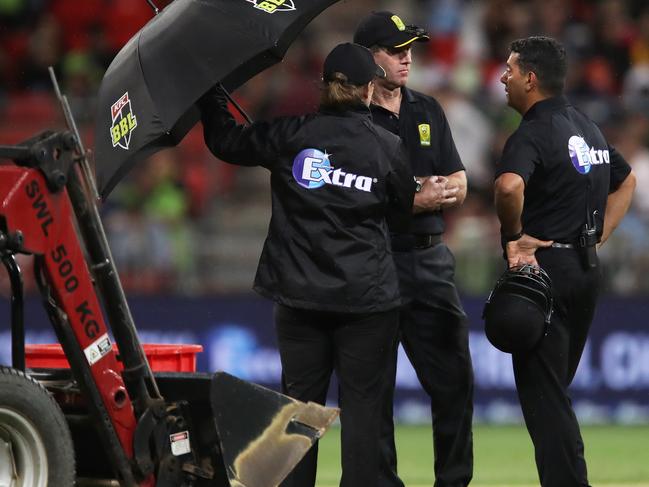 Umpires Gerard Abood and Tony Wilds speak during a rain delay.