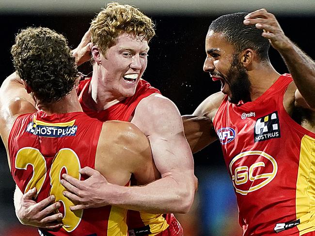 Suns players Jarrod Witts and Touk Miller (right) celebrate after Matthew Rowell (left) kicked a goal during the Round 4 AFL match between the Gold Coast Suns and the Fremantle Dockers at Metricon Stadium on the Gold Coast, Saturday, June 27, 2020. (AAP Image/Dave Hunt) NO ARCHIVING, EDITORIAL USE ONLY