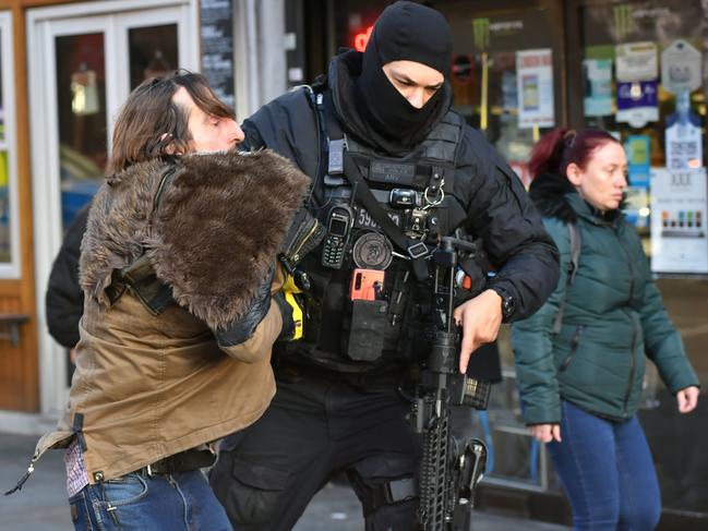 A police officer moves an uninvolved person away from a cordon after the attack. Picture: AP