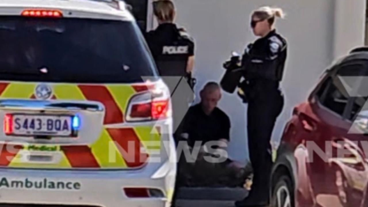 Shaun Dunk sitting on the ground outside of REAL Estate Agents Group, where it’s alleged inside he stabbed one employee to death and seriously injured another. Picture 7News