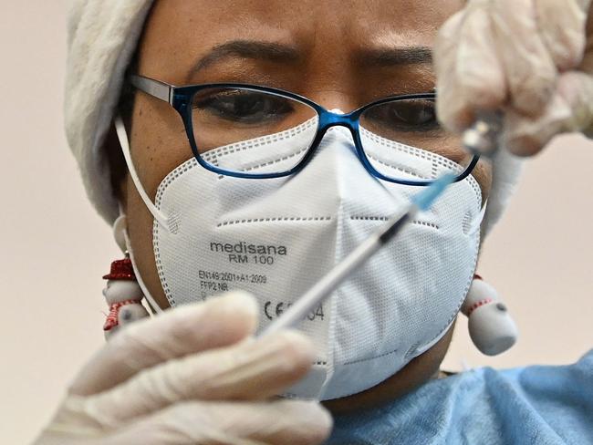 A NHS health worker prepares a dose of the Covid-19 vaccine at a pop-up coronavirus vaccination centre at the Redbridge Town Hall, east London on December 25, 2021. - British Prime Minister Boris Johnson in his Christmas Eve message exhorted the UK public to get jabbed as a "wonderful" gift for the nation as cases soar. (Photo by JUSTIN TALLIS / AFP)