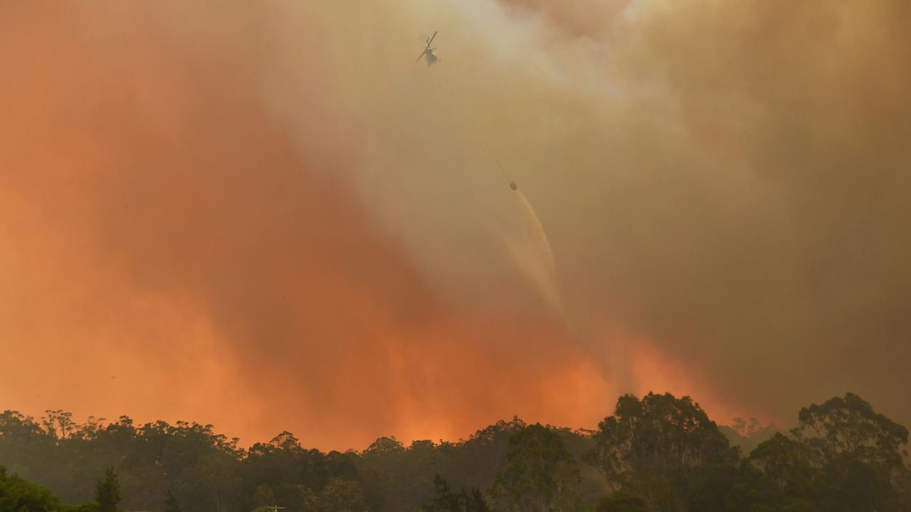 A helicopter drops water on a property atNana Glen, near Coffs Harbour. Picture: AFP