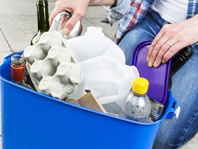 Woman filling a blue recycling bin the wrong way.