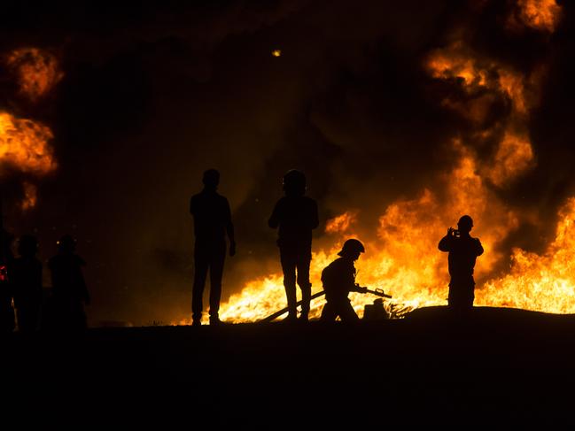 An Israeli firefighter battles a field fire after a rocket launched from Gaza Strip. Picture: Getty