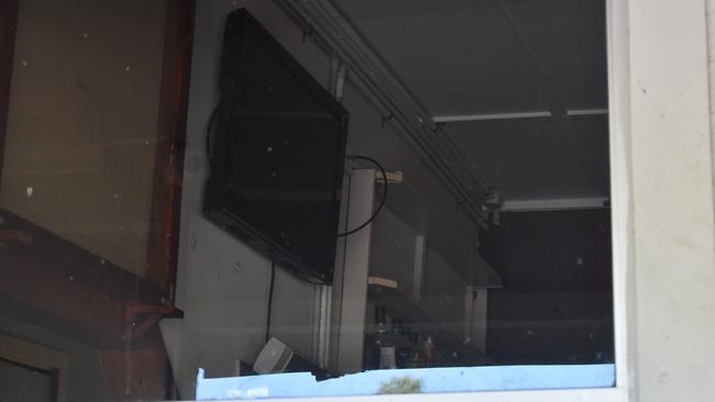 Inside one of the windows of the Bouldercombe Royal Hotel, liquor bottles on the bar and a television still hangs on the wall.