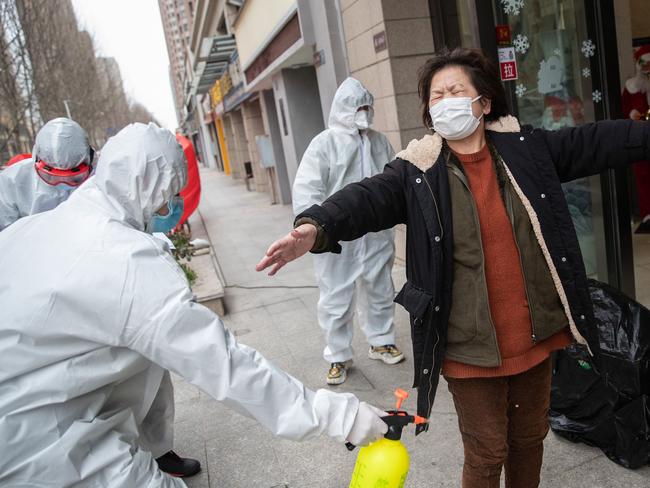 A woman who has recovered from the coronavirus infection is disinfected as she arrives at a hotel for a 14-day quarantine after being discharged from a hospital in Wuhan. Picture: AFP