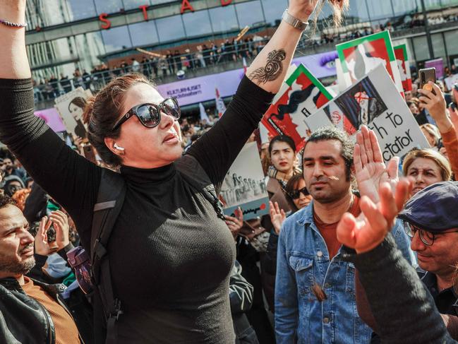 A woman cuts her hair during a demonstration in Sergels Torg in Stockholm, Sweden on September 24, 2022, following the death of an Iranian woman after her arrest by the country's morality police in Tehran. - Protests in Iran following the death of a young woman arrested by morality police could signal "a big change", according to Mahmood Amiry-Moghaddam, director of Oslo-based NGO Iran Human Rights (IHR). Public anger has flared in the Islamic republic since authorities announced the death last week of 22-year-old Mahsa Amini, who had been held for allegedly wearing a hijab headscarf in an "improper" way. (Photo by Fredrik PERSSON / TT NEWS AGENCY / AFP)