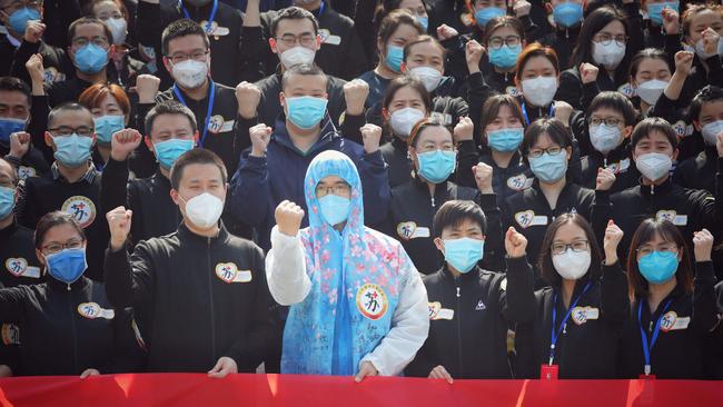 Members of a medical assistance team from Jiangsu province chant slogans at a ceremony marking their departure from Wuhan in Hubei province, where China is claiming no new coronavirus cases have been recorded. Picture: AFP