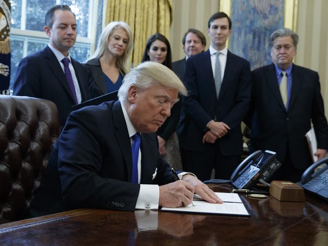 President Donald Trump signs an executive order on January 24 in the Oval Office of the White House in Washington. Picture: AP/Evan Vucci.