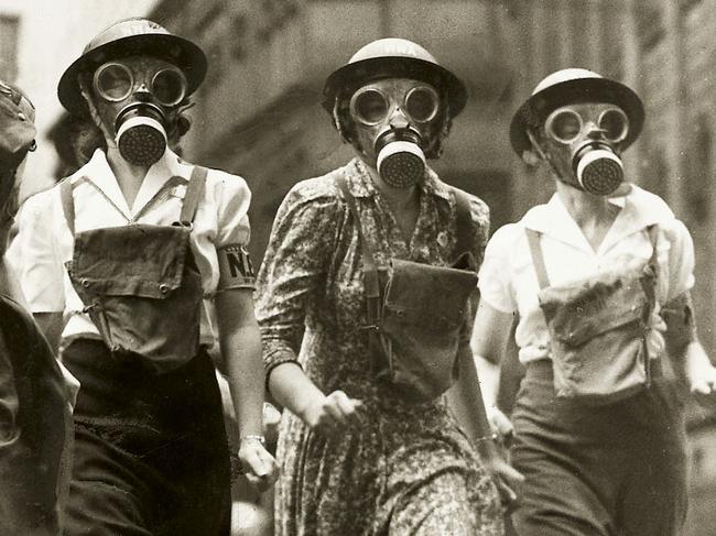 Photograph of five women wearing gas masks running down a city street in competition held in city between different emergency service teams in circa 1943 photo during World War Two (II), part of Sydney in WWII Homefront exhibition at Sydney Museum in Sydney.