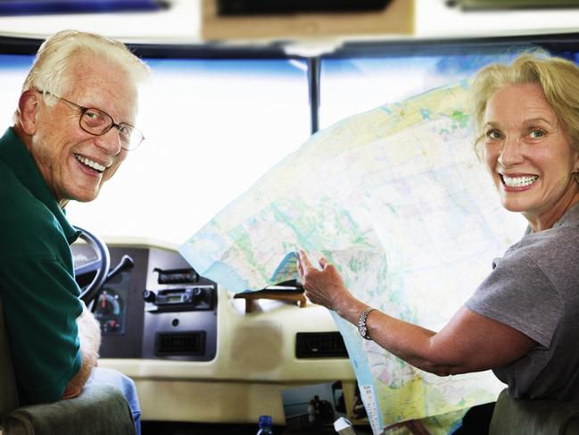 A happy senior couple sitting in the front seats of their RV looking at a map.