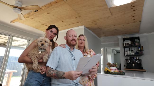 Janie Lee Clogan, 17, and dog Lucy with Aaron Hope and partner Lee Clogan at their Oxenford home looking at renewal documents showing their insurance premium had more than doubled after the Christmas Day tornado. Picture: Glenn Hampson.