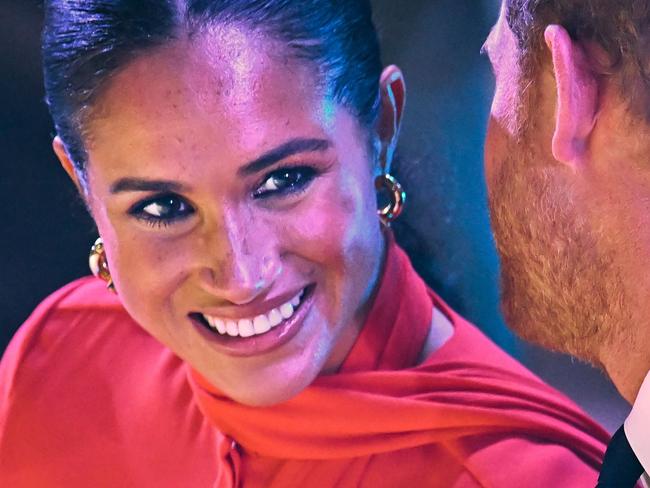 Meghan smiles as Prince Harry whispers in her ear. Picture: AFP