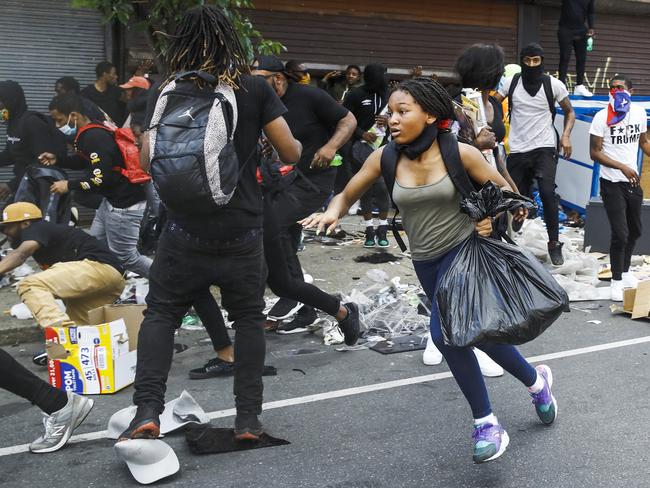 People run from the area as police officers approach stores that were broken into as protests continued in Philadelphia. Picture: AP