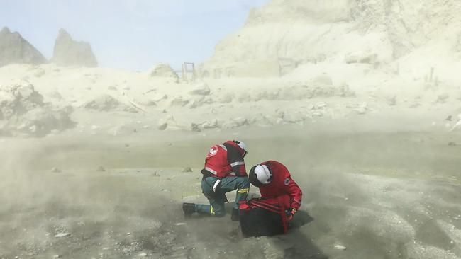 Rescuers shelter from a maelstrom of ash as their helicopter takes off after Monday’s volcanic eruption. Picture: Auckland Rescue Helictoper Trust