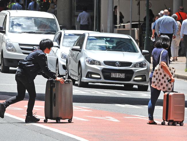 People using the phone while crossing Adelaide Street. Picture: AAP image/John Gass