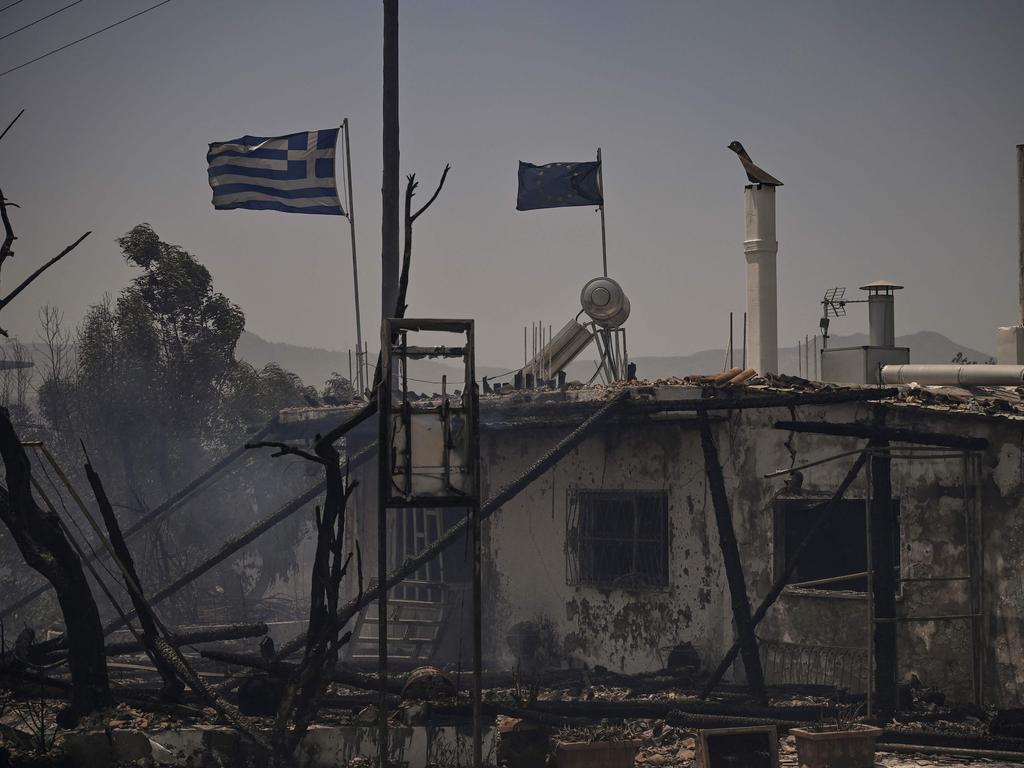 Greek and European flags on a burnt building amid a fire between the villages of Kiotari and Genadi, on the Greek island of Rhodes. Picture: AFP