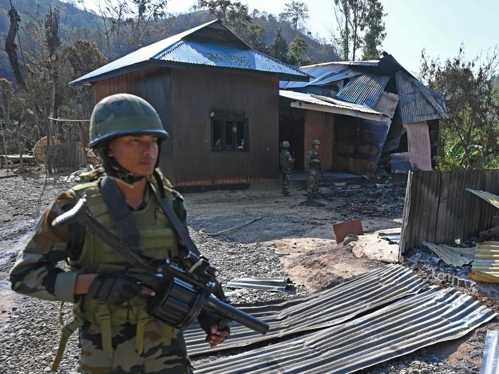 Indian army soldiers inspect the remains of a house that was set on fire by a mob in the ethnic violence hit area of Senapati district.