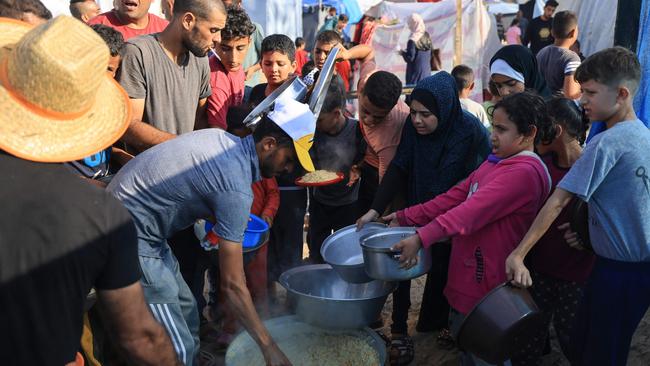 People distribute food at a makeshift camp for displaced people in Khan Yunis in the southern Gaza Strip. Photo: Mahmud HAMS / AFP