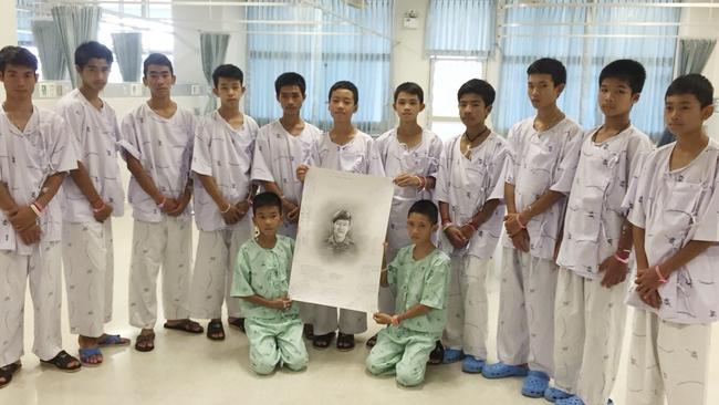 The rescued soccer team members posing with a sketch of the Thai Navy SEAL diver who died while trying to rescue them.