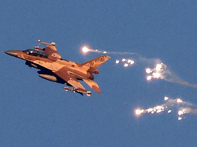 This photo taken from a position in northern Israel shows an Israeli Air Force fighter jet firing flares as it flies to intercept a hostile aircraft that launched from Lebanon over the border area with south Lebanon on August 25, 2024. The Israeli military announced early August 25, 2024 that it was conducting pre-emptive strikes in Lebanon after detecting preparations for "large-scale" attacks by the Iran-backed militant group Hezbollah. Hezbollah said August 25, 2024 it had launched more than 320 rockets at Israel overnight, targeting a string of military positions, even as Israel's military said it was carrying out pre-emptive strikes against the group. (Photo by Jalaa MAREY / AFP)