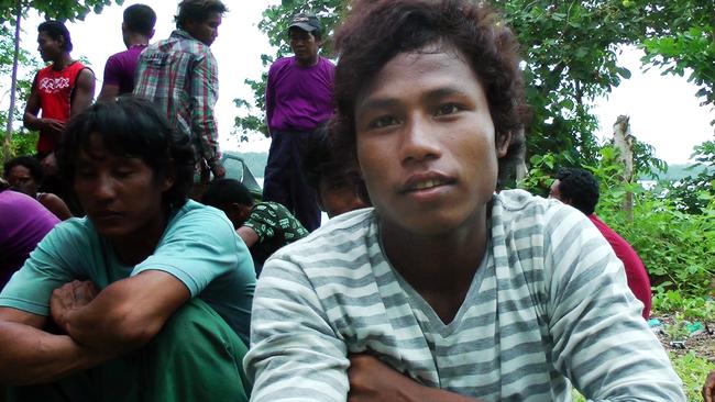 Tun Lin Maung sits with a group of slave fishermen from Myanmar behind a fishing company building in Benjina, Indonesia. Maung says it has been two years since he escaped from his Thai fishing trawler, where he and other slaves worked day and night, wrangling giant nets filled with red snapper, grouper and squid onto the deck and then sorting them by species.