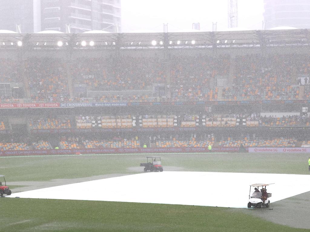 Groundsmen covered the pitch area after rain stopped play on day four of the Gabba Test. Picture: Patrick Hamilton/ AFP