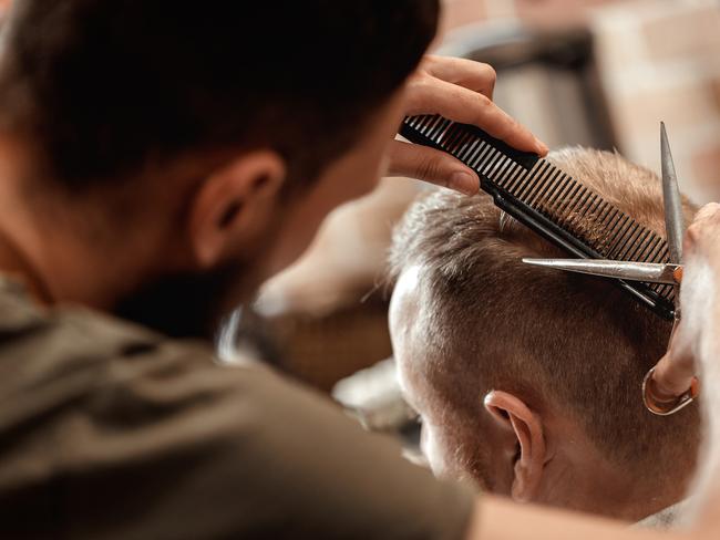 Generic male hairdresser does haircut for bearded man in barber shop. Source: iStock