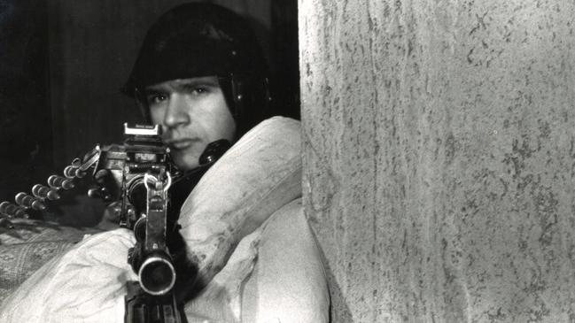 A Romanian soldier braves the freezing winter weather wrapped in a doona looking down the sight of his rifle. Picture: Hedley Thomas