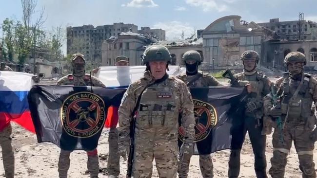 Yevgeny Prigozhin stands in front of a Russian national flag in front of his soldiers holding Wagner Group's flags in Bakhmut. Picture: AFP.