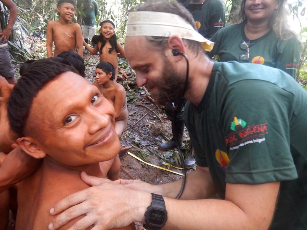 A Korubo man smiles up at the camera as a FUNAI member checks his heart rate during the expedition to the Javari Valley, in Brazil. Picture: Brazil's National Indian Foundation Photo via AP