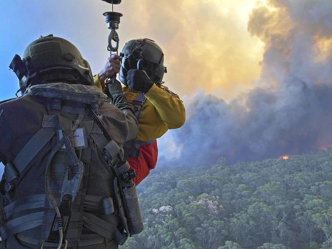 Rural Fire Service employee, Mr Allen Madden prepares to be winched down in the Lithgow area by Petty Officer Aircrewman Jason Wickman from an 808 Squadron MRH90 Taipan Military Support Helicopter over the Grose Valley bushfire in the Blue Mountains National Park. *** Local Caption *** The Australian Defence Force (ADF) is continuing to support Emergency Management Australia in firefighting efforts around the country.  Navy’s MRH-90 Taipan helicopters based at HMAS Albatross in Nowra have evacuated residents at risk on the New South Wales South Coast and continue with day and night time aerial fire mapping. An additional MRH-90 forward-deployed to western Sydney, has facilitated access by specialist RFS personnel to properties under threat from advancing fire in the Hartley Vale region. The helicopter was also tasked to support personnel evacuation and property assessment in the Blue Mountains – Lithgow region. ADF liaison officers are working side by side with emergency services personnel in the State Disaster Coordination Centre (SDCC) and within the New South Wales Rural Fire Service Headquarters.  Defence is also providing transport and other capabilities such as aviation ground support, logistics, engineering and accommodation to support the firefighting effort.