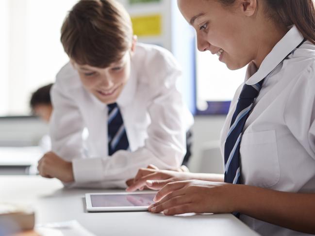 Two High School Students Wearing Uniform Working Together At Desk Using Digital Tablet Picture: Istock