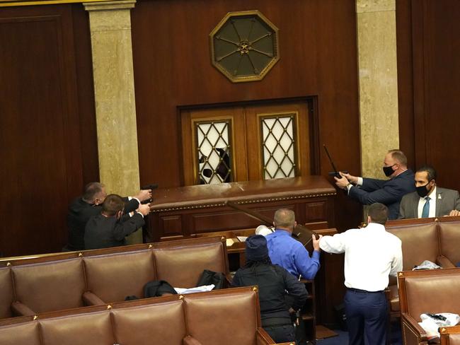 Law enforcement officers point their guns at a door that was vandalised in the House Chamber during a joint session of Congress. Picture: Getty