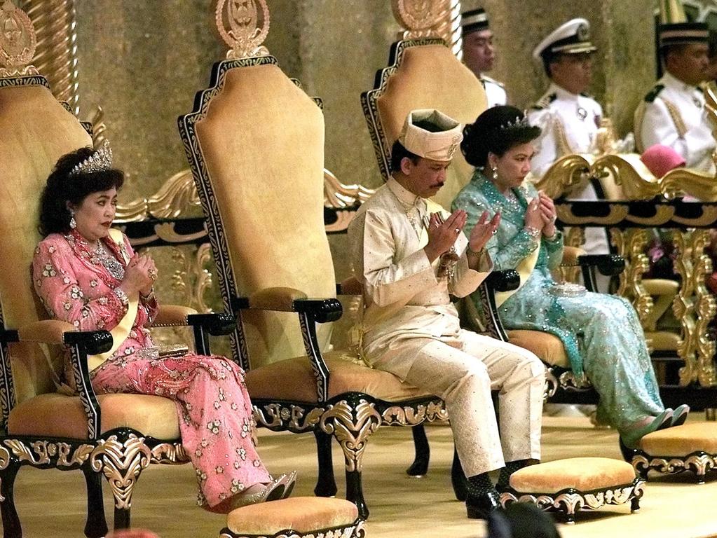 The Sultan of Brunei Hassanal Bolkiah offers a prayer in 2000 with two of his wives at a royal birthday investiture in Nurul Iman Palace.