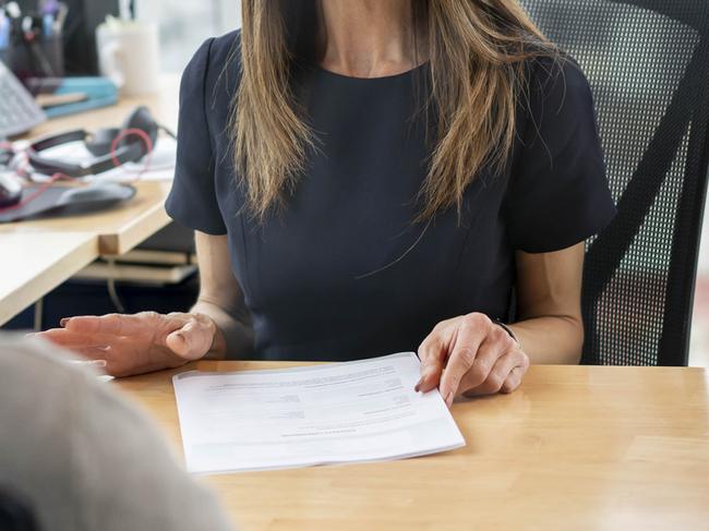 HR manager at her office talking to employee cheerfully while holding some paperwork