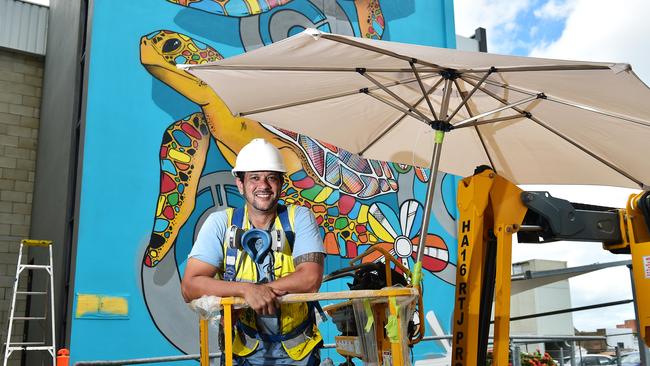 Darwin artist Hafleg puts the finishing touches to his street art mural which is on the side of the city police station. Picture: Shae Beplate.