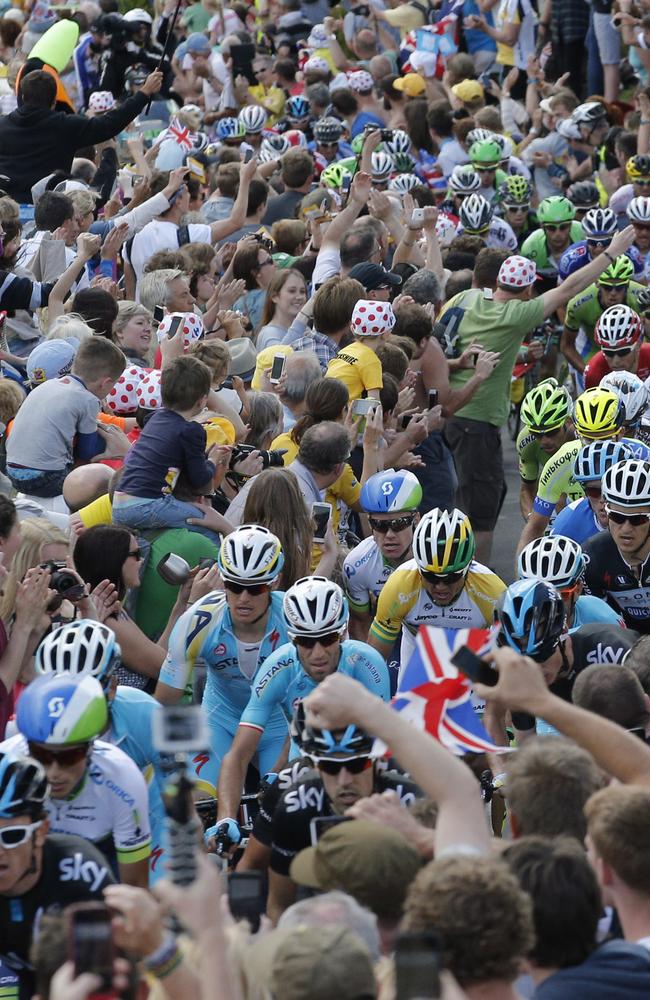 Stage winner and new overall leader Italy's Vincenzo Nibali, centre (above the clenched fist) with Simon Gerrans right behind struggle to find room through the crowds.