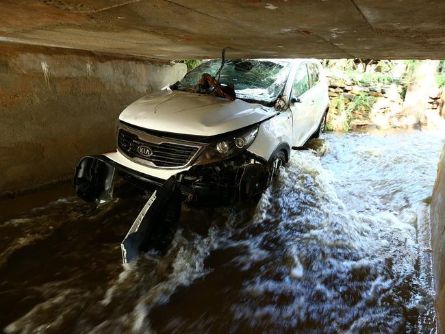 A car shows its damage after it was washed downstream under a bridge at Waterfall Gully. Picture: Tait Schmaal.