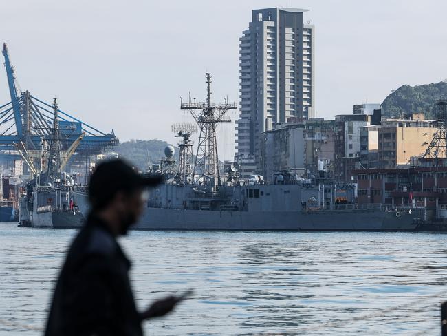 TOPSHOT - A man stands before Taiwanese Navy ships anchored at the harbour in Keelung on December 11, 2024. Taiwan said on December 11 it had detected 53 Chinese military aircraft and 19 ships near the island in the past 24 hours, as Beijing holds its biggest maritime mobilisation in years. (Photo by I-Hwa CHENG / AFP)